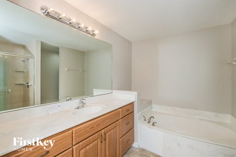 A bathroom with a white tub and a wooden vanity.