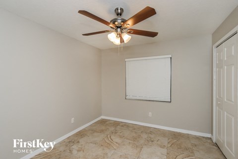 A room with a ceiling fan and a whiteboard on the wall.