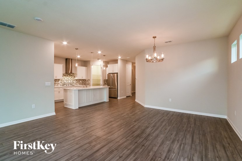 A spacious room with wooden flooring and a chandelier hanging from the ceiling.