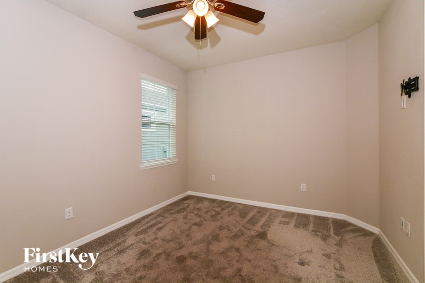 A room with a ceiling fan and a window with blinds.