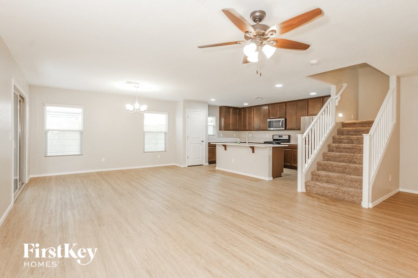 an open kitchen and living room with a staircase and a ceiling fan