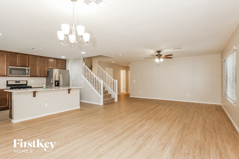 an empty living room with a kitchen and a staircase