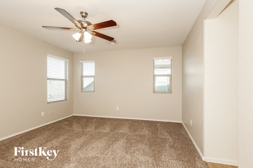 the spacious living room with ceiling fan and carpeting