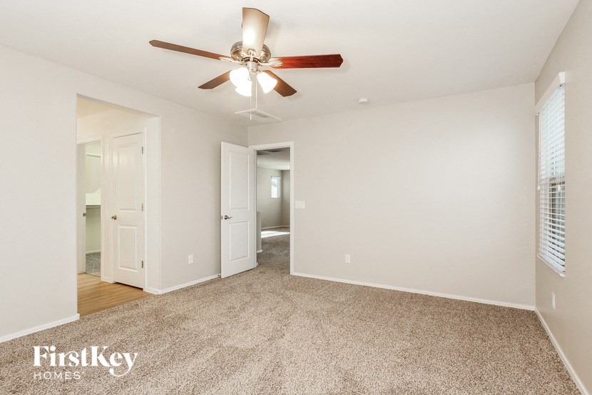 a spacious living room with a ceiling fan and white walls