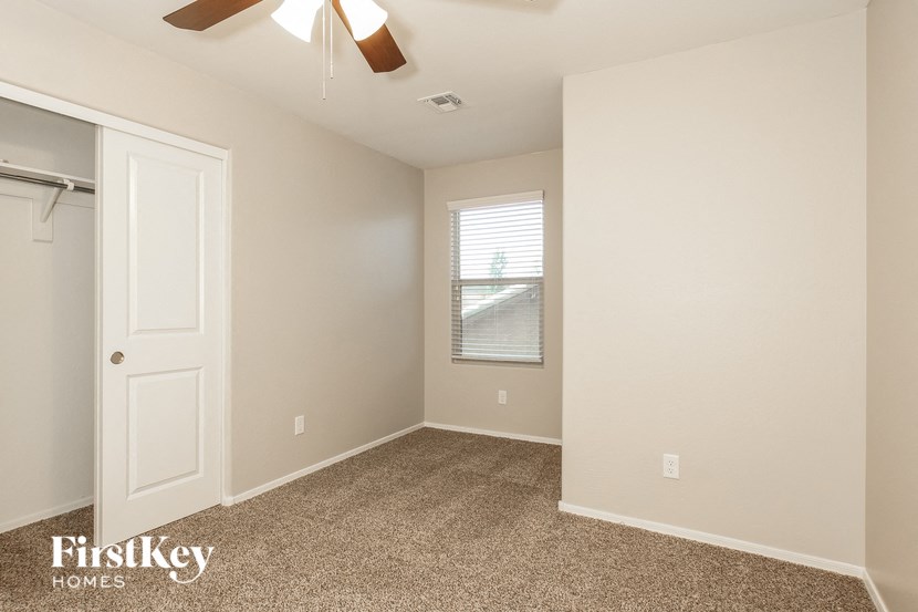 a bedroom with a closet and a window and a ceiling fan