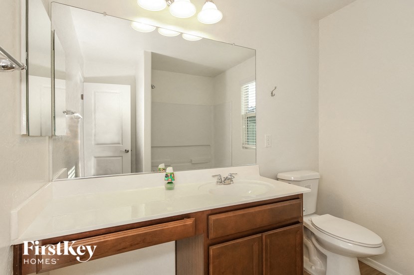 a bathroom with a large mirror and a sink and a toilet