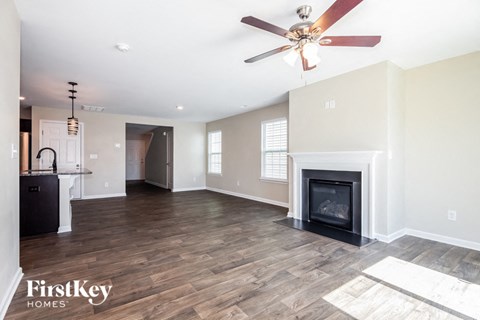 A spacious living room with a fireplace and a ceiling fan.