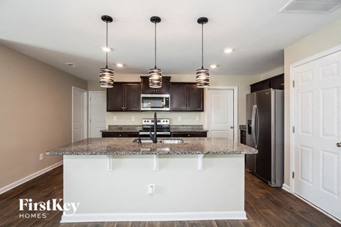 A kitchen with a granite countertop and a refrigerator in the background.