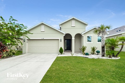 a beige house with a lawn and palm trees