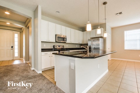 a kitchen with white cabinets and a black counter top