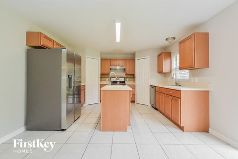 A kitchen with a refrigerator, cabinets, and a counter.