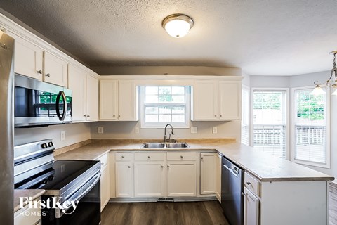 A kitchen with white cabinets and a black dishwasher.