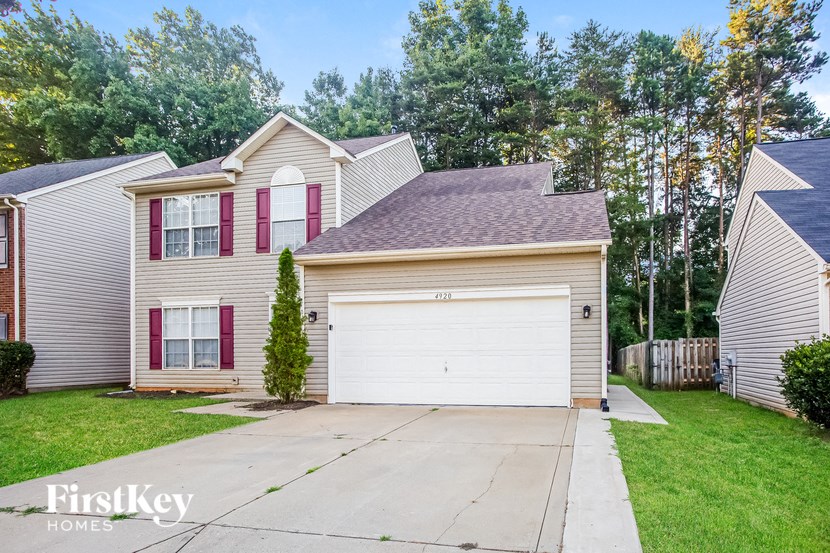 a beige house with red shutters and a white garage door