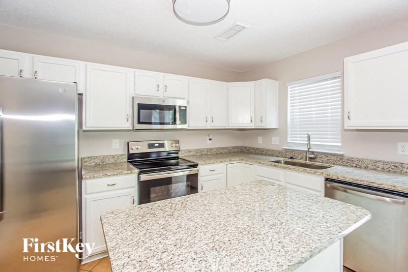 a kitchen with white cabinets and granite counter tops and stainless steel appliances