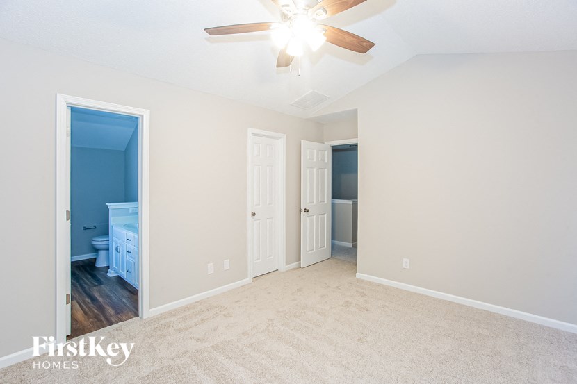 a living room with a ceiling fan and a door to a bathroom
