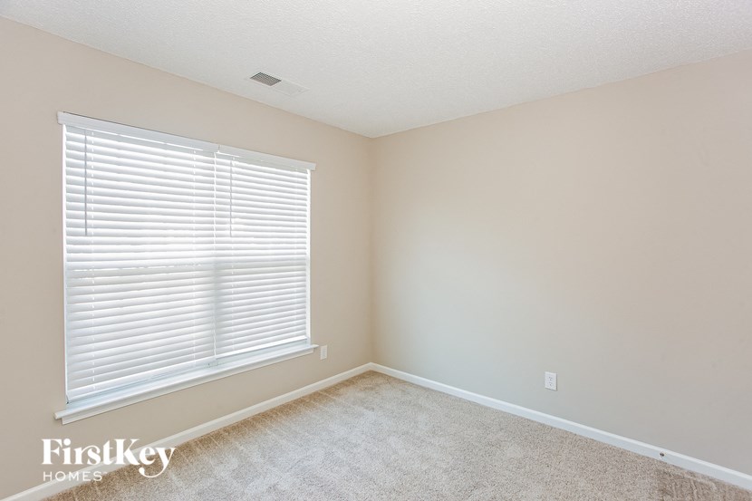 a bedroom with a large window and a carpeted floor