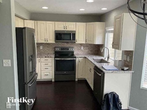 A kitchen with a refrigerator, microwave, oven, and sink.