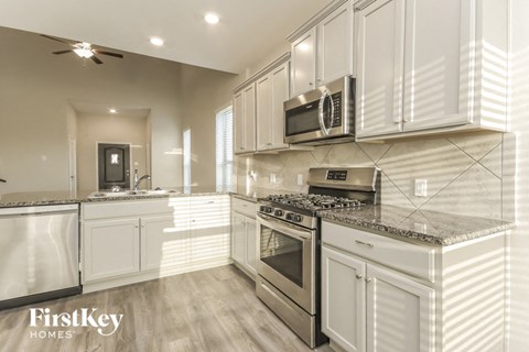 A modern kitchen with white cabinets and stainless steel appliances.