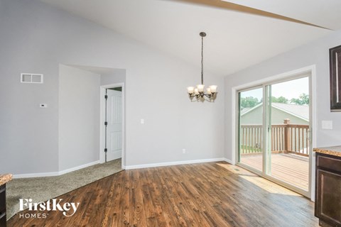 an empty living room with wood flooring and sliding glass doors to a deck