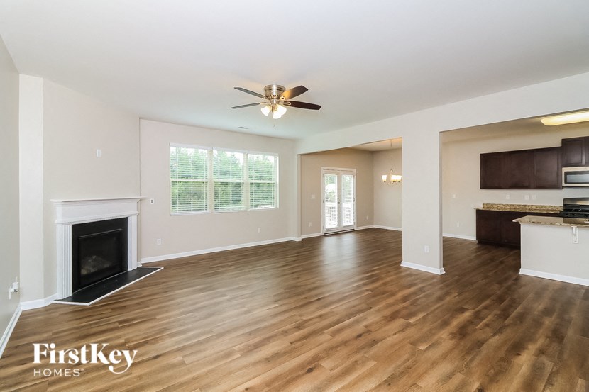 A spacious living room with wood flooring and a fireplace.