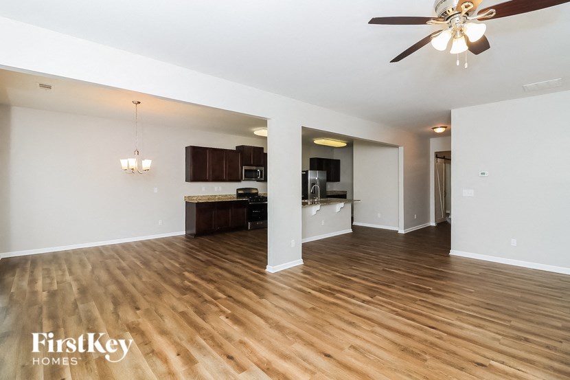 A spacious living room with wooden floors and a ceiling fan.