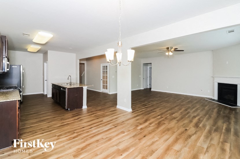 A large, empty living room with wooden floors and a fireplace.