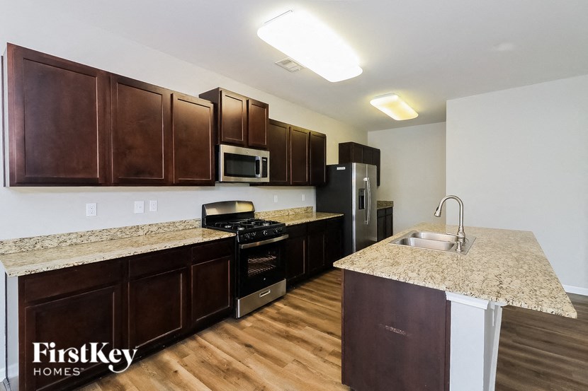 A kitchen with brown cabinets and a granite counter top.