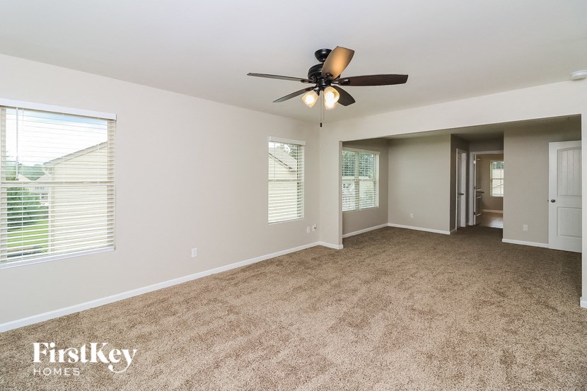 A spacious room with a ceiling fan and carpeted floor.