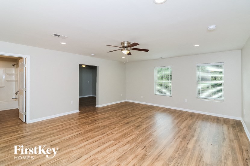 A spacious room with a ceiling fan and wooden flooring.