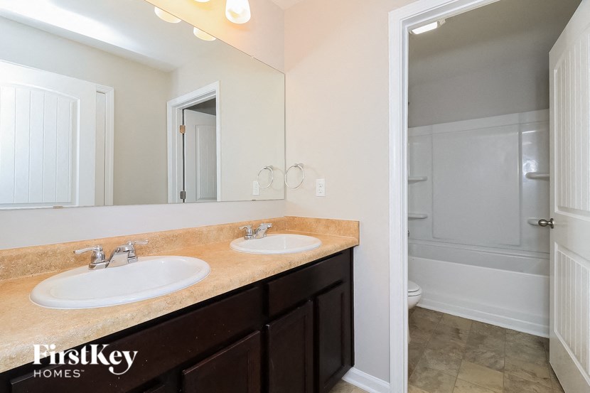A bathroom with a tan counter top and a white sink.