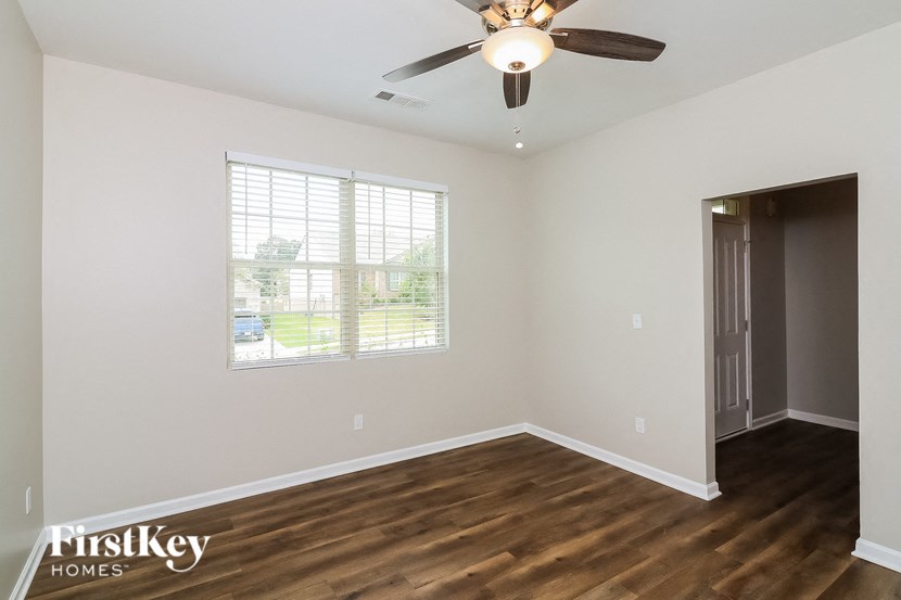 A room with a ceiling fan and a window with blinds.