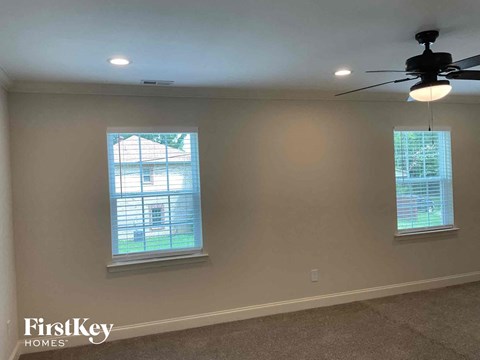 a living room with two windows and a ceiling fan