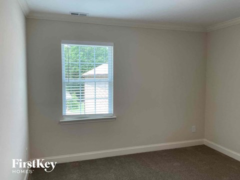 a bedroom with a window and a carpeted floor