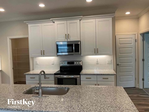 an updated kitchen with white cabinets and granite counter tops