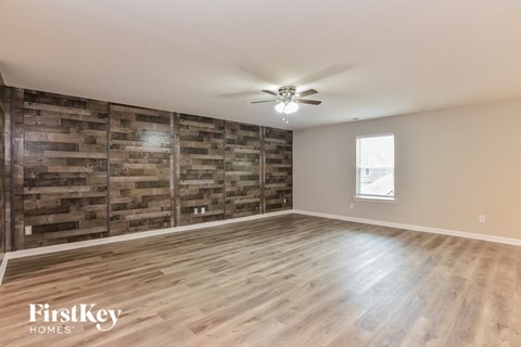 A spacious room with wooden flooring and a wall made of wooden planks.