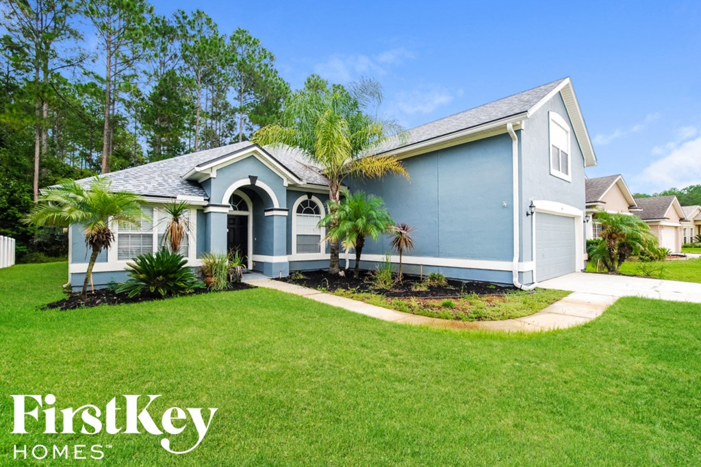 a blue house with a lawn and palm trees