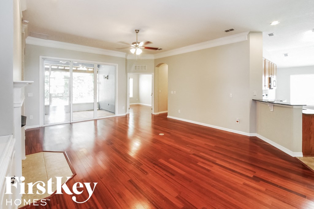 an empty living room with wood floors and a ceiling fan