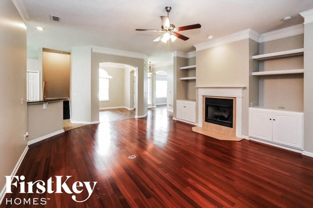 an empty living room with a fireplace and a ceiling fan