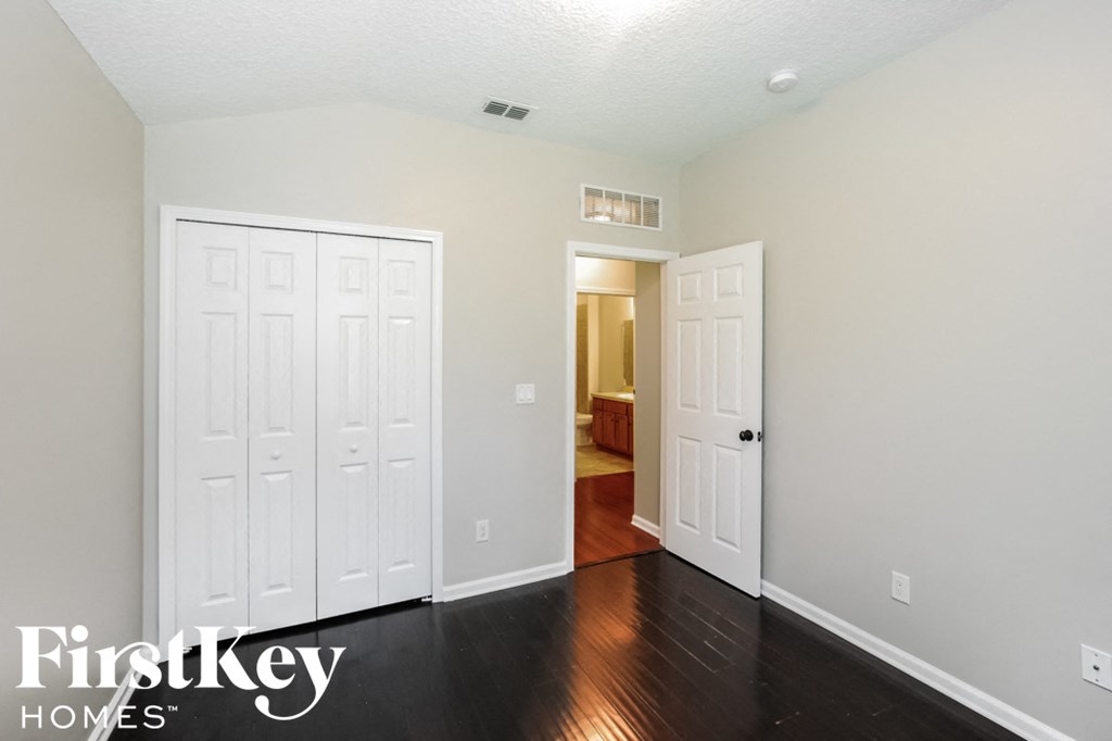 a bedroom with two closets and a door to a hallway with a door open