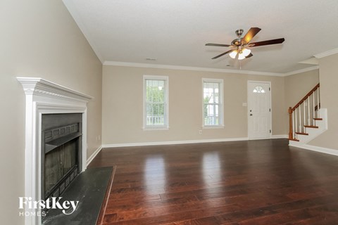 an empty living room with a fireplace and a ceiling fan