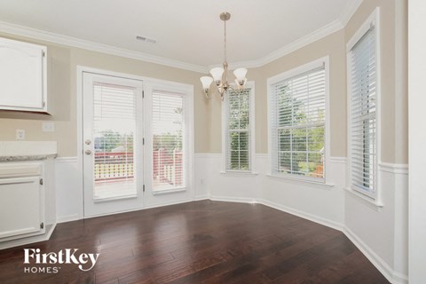 an empty dining room with windows and a door to a balcony
