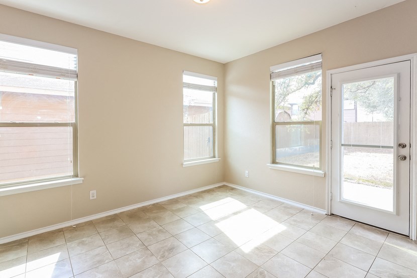 A room with a white door, two windows, and a tiled floor.