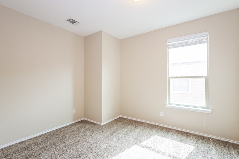 A room with a window and carpet on the floor.