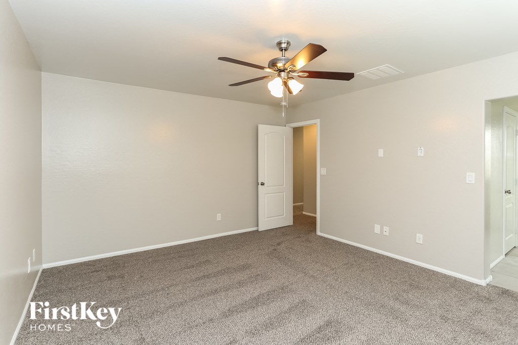 a spacious living room with carpet and a ceiling fan