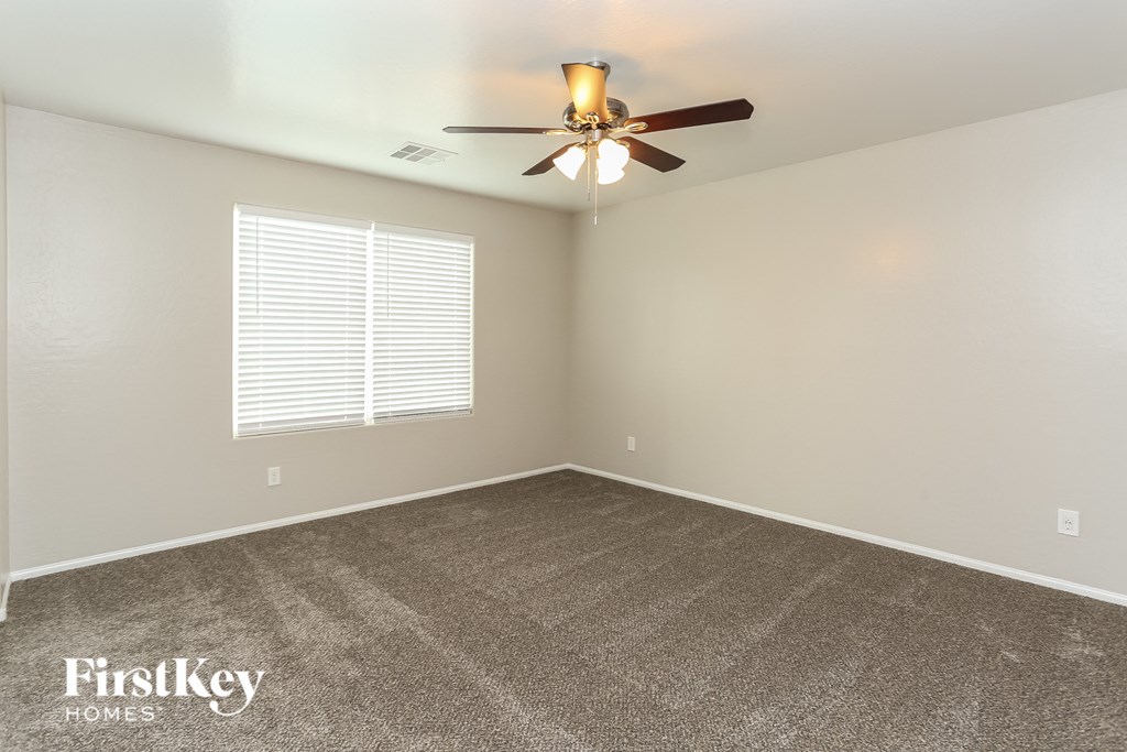 the spacious living room with ceiling fan and carpet