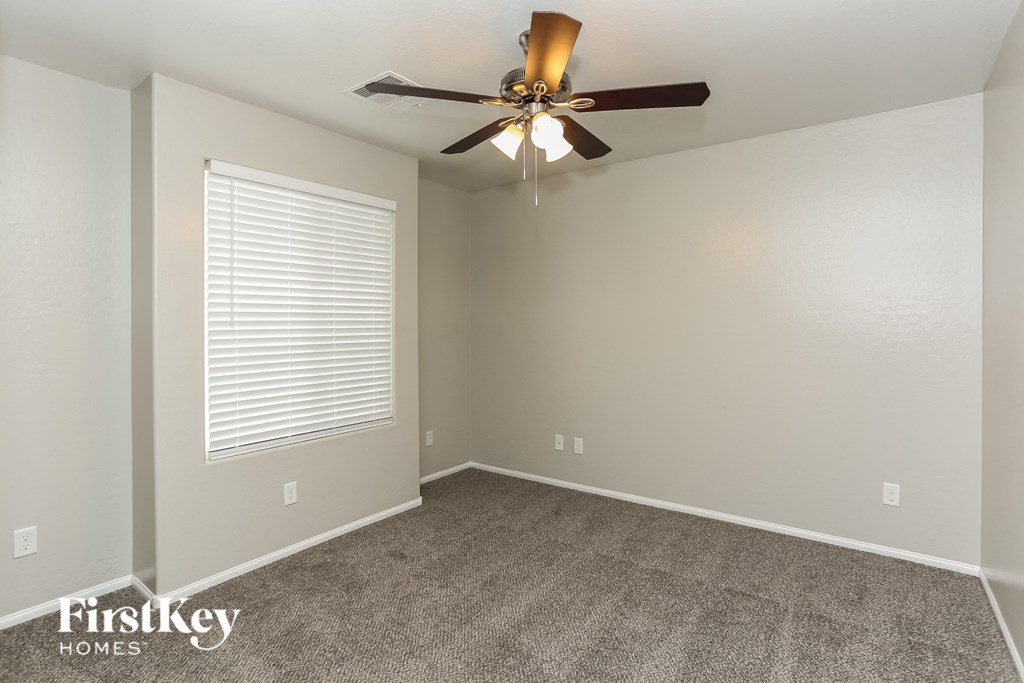 the spacious living room with ceiling fan and carpet