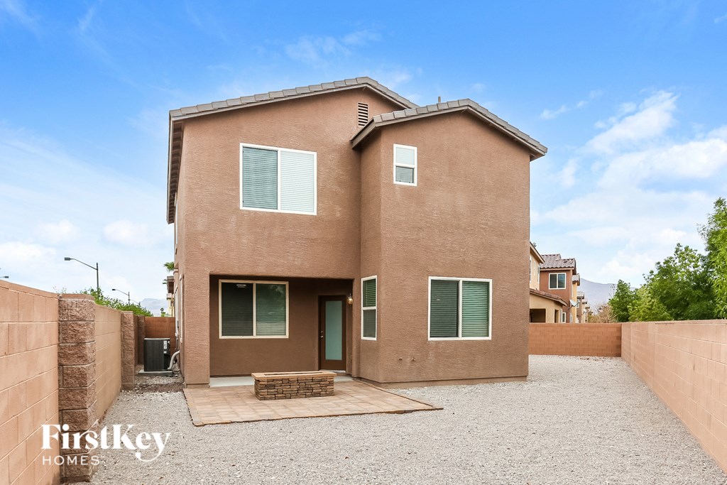 a brick house with green shutters and a gravel driveway