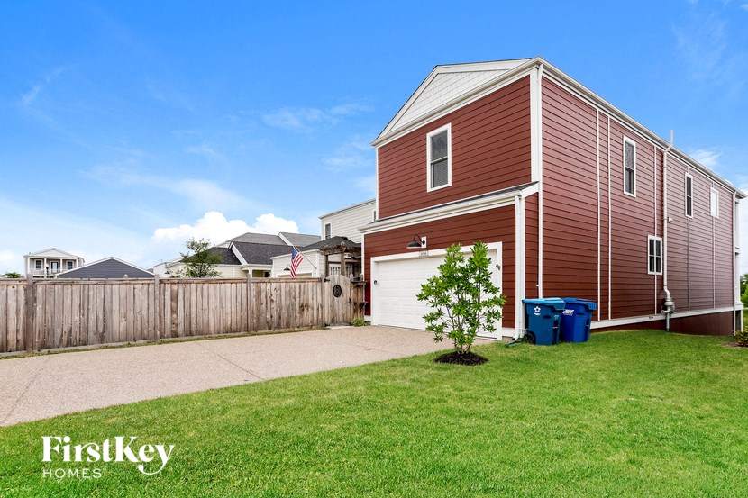 a red house with a yard and a fence and a driveway