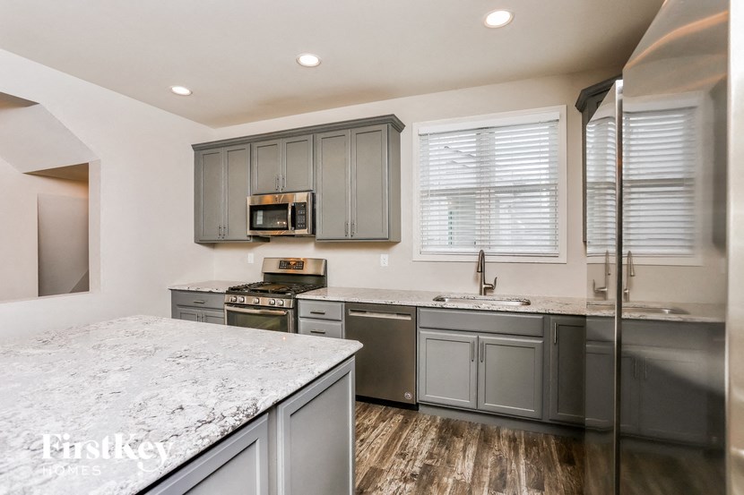 a kitchen with gray cabinets and white counter tops and stainless steel appliances
