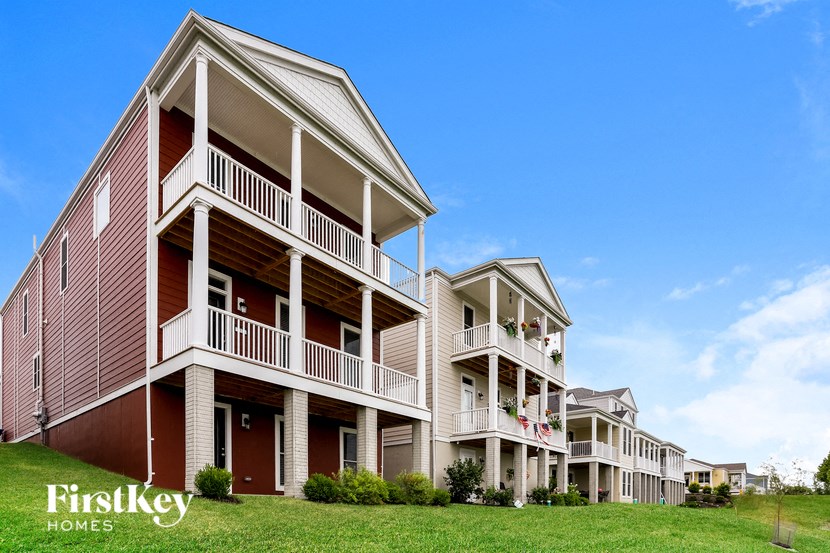 a row of three story houses with balconies and a lawn